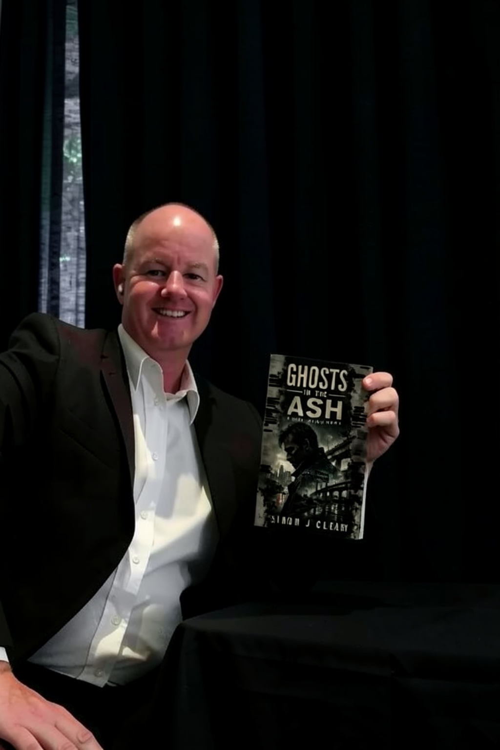 Simon J Cleary holding a copy of Ghosts in the Ash